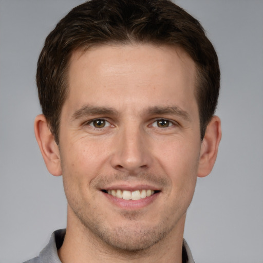 Joyful white young-adult male with short  brown hair and grey eyes