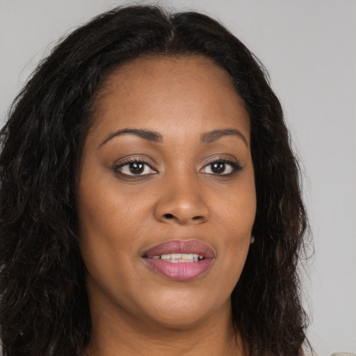 Joyful black young-adult female with long  brown hair and brown eyes