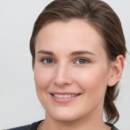 Joyful white young-adult female with medium  brown hair and grey eyes