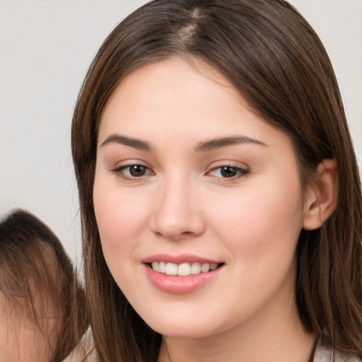 Joyful white young-adult female with long  brown hair and brown eyes