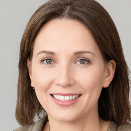 Joyful white young-adult female with medium  brown hair and grey eyes