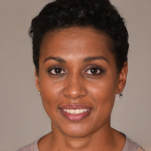 Joyful black young-adult female with short  black hair and brown eyes