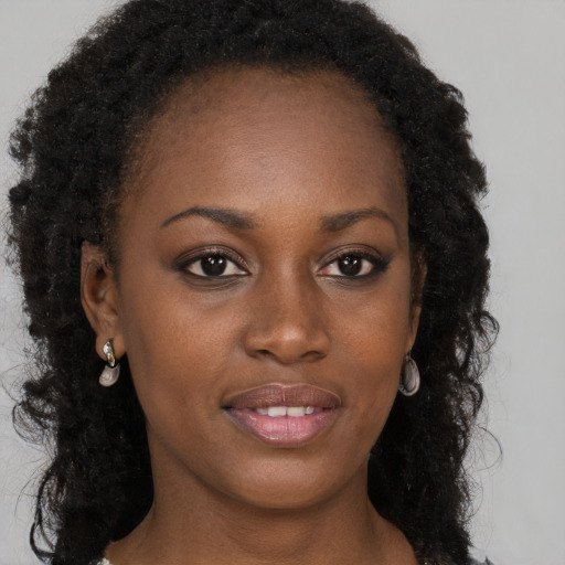 Joyful black young-adult female with long  brown hair and brown eyes