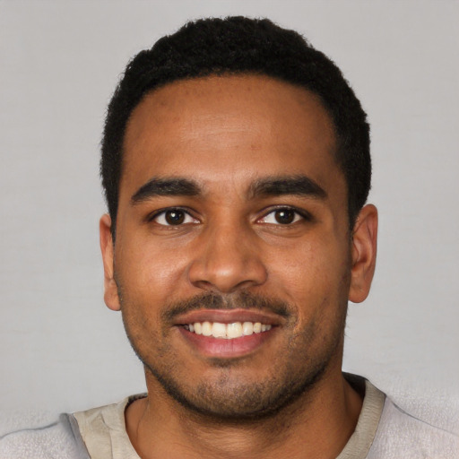 Joyful black young-adult male with short  black hair and brown eyes