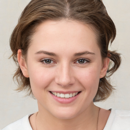 Joyful white young-adult female with medium  brown hair and grey eyes