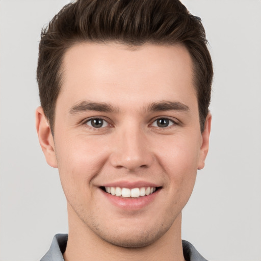 Joyful white young-adult male with short  brown hair and grey eyes