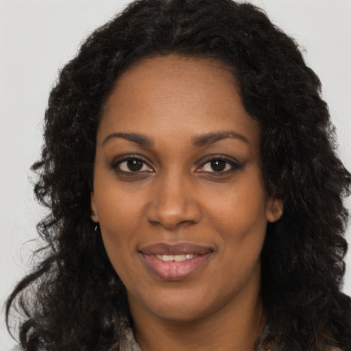Joyful black young-adult female with long  black hair and brown eyes
