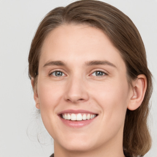 Joyful white young-adult female with medium  brown hair and grey eyes