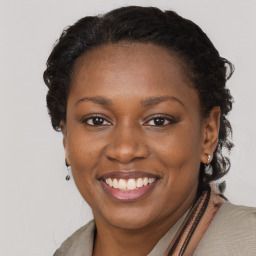 Joyful black young-adult female with long  brown hair and brown eyes