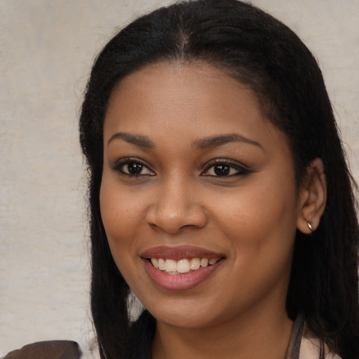 Joyful black young-adult female with long  brown hair and brown eyes