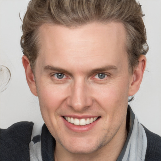 Joyful white adult male with short  brown hair and blue eyes