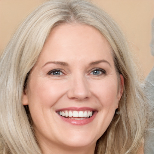 Joyful white adult female with long  blond hair and blue eyes