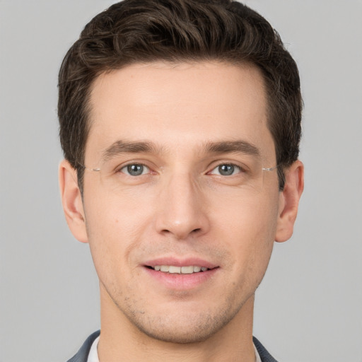 Joyful white young-adult male with short  brown hair and grey eyes