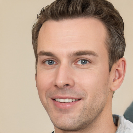 Joyful white young-adult male with short  brown hair and grey eyes