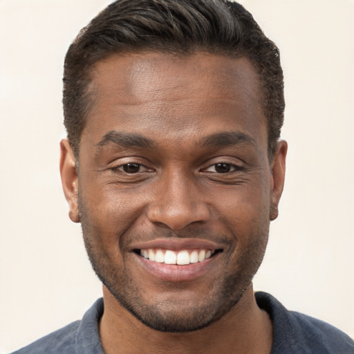 Joyful black young-adult male with short  brown hair and brown eyes