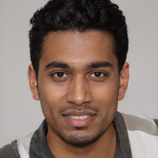 Joyful latino young-adult male with short  black hair and brown eyes
