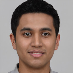 Joyful latino young-adult male with short  black hair and brown eyes