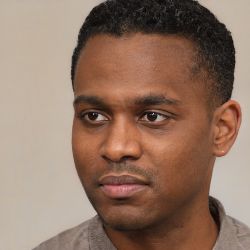 Joyful black young-adult male with short  black hair and brown eyes
