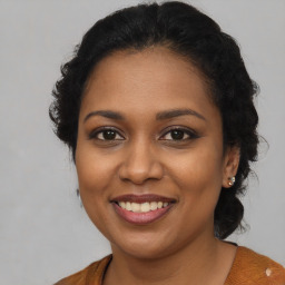 Joyful black young-adult female with long  brown hair and brown eyes