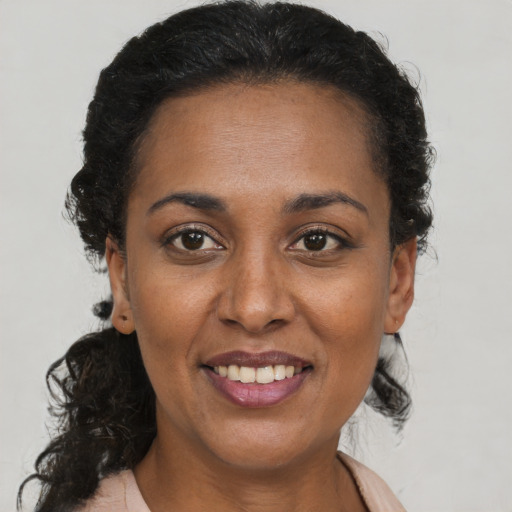 Joyful black adult female with medium  brown hair and brown eyes