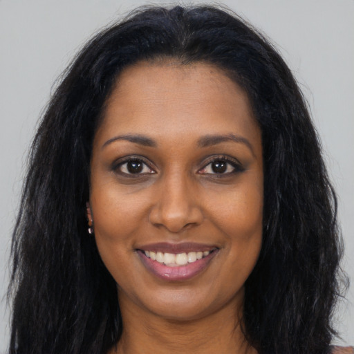 Joyful black young-adult female with long  black hair and brown eyes