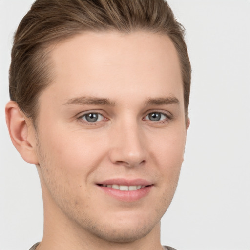 Joyful white young-adult male with short  brown hair and grey eyes