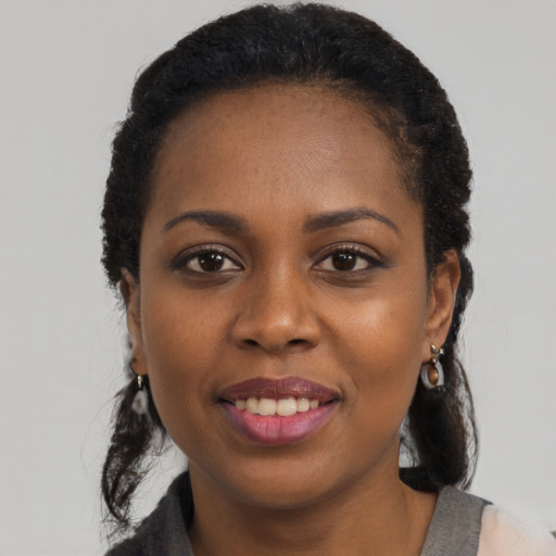 Joyful black young-adult female with long  black hair and brown eyes
