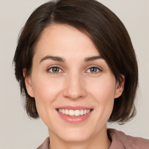 Joyful white young-adult female with medium  brown hair and grey eyes