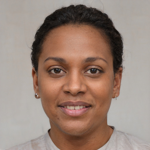 Joyful black young-adult female with short  black hair and brown eyes
