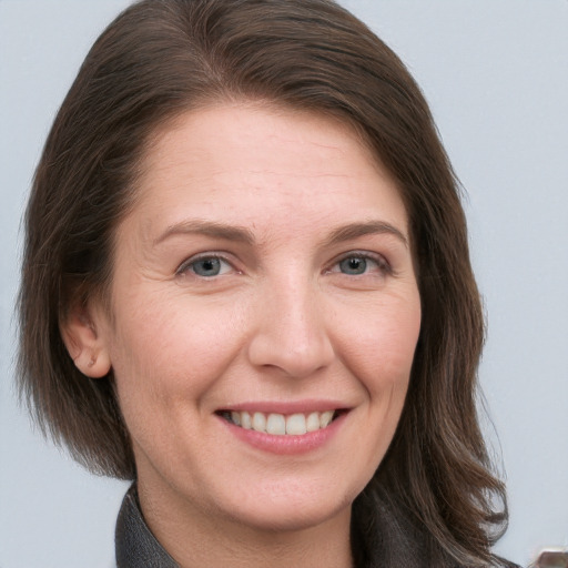 Joyful white adult female with long  brown hair and grey eyes