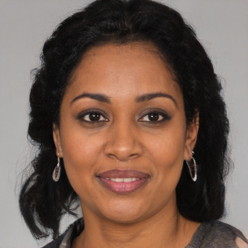 Joyful black adult female with long  brown hair and brown eyes