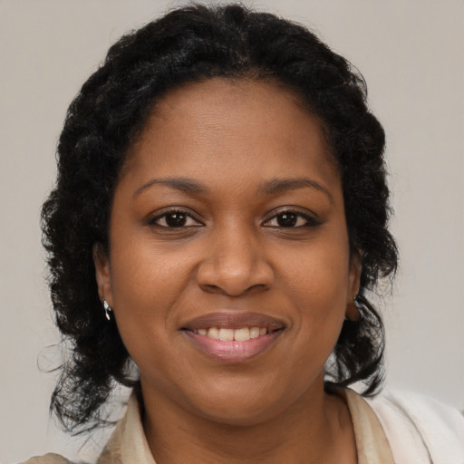 Joyful black young-adult female with long  brown hair and brown eyes