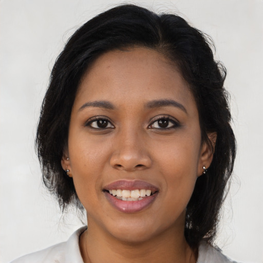 Joyful black young-adult female with long  brown hair and brown eyes