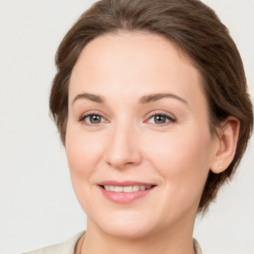 Joyful white young-adult female with medium  brown hair and grey eyes