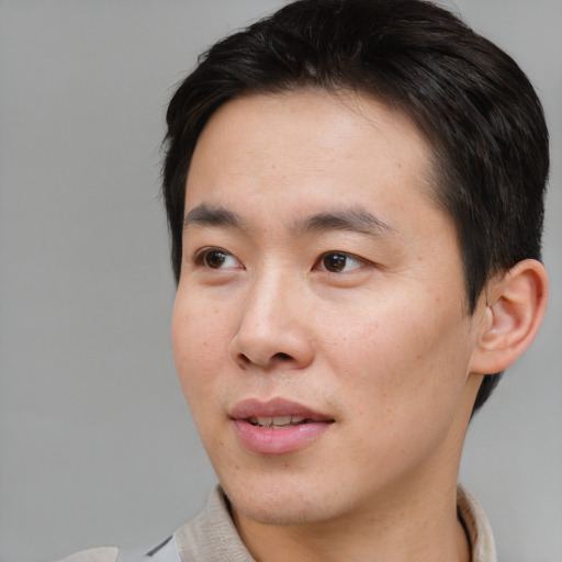 Joyful asian young-adult male with short  brown hair and brown eyes