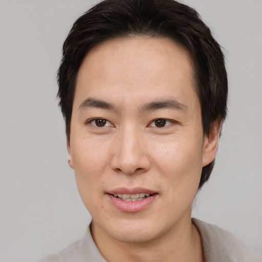 Joyful asian young-adult male with short  brown hair and brown eyes