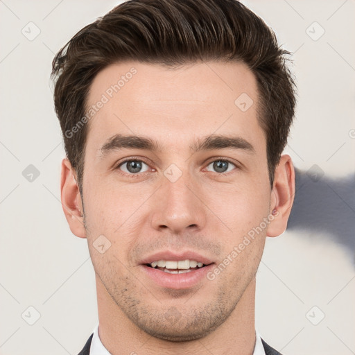 Joyful white young-adult male with short  brown hair and grey eyes