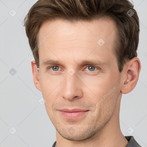 Joyful white young-adult male with short  brown hair and grey eyes