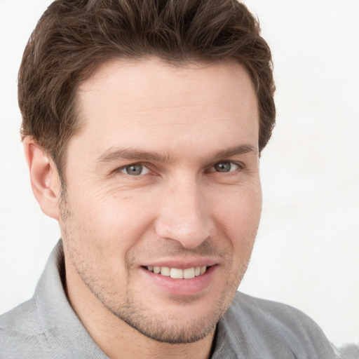 Joyful white young-adult male with short  brown hair and grey eyes