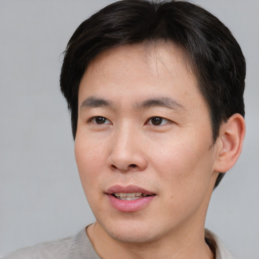 Joyful asian young-adult male with short  brown hair and brown eyes