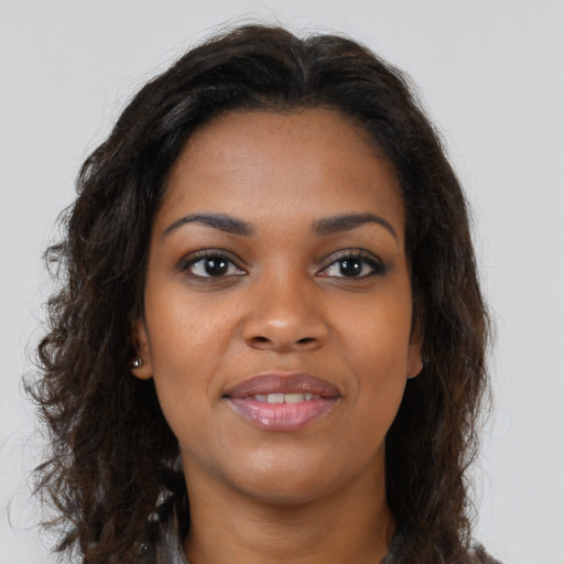 Joyful black young-adult female with long  brown hair and brown eyes