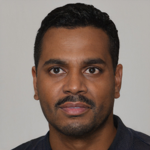 Joyful black young-adult male with short  black hair and brown eyes