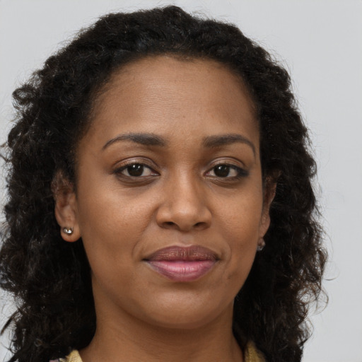 Joyful black adult female with long  brown hair and brown eyes