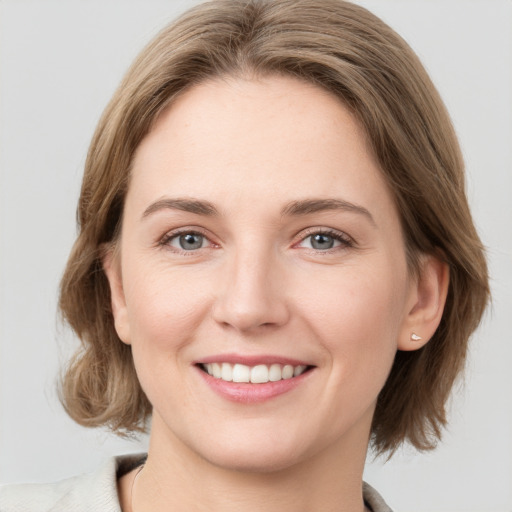 Joyful white young-adult female with medium  brown hair and grey eyes