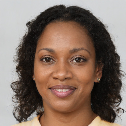 Joyful black young-adult female with long  brown hair and brown eyes