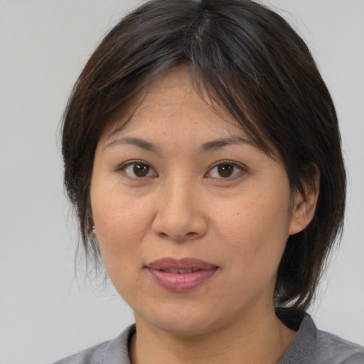Joyful asian adult female with medium  brown hair and brown eyes