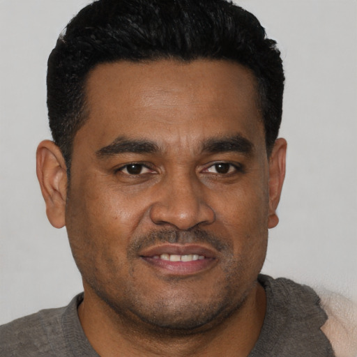 Joyful black young-adult male with short  black hair and brown eyes