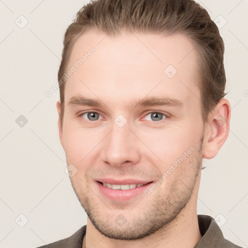 Joyful white young-adult male with short  brown hair and grey eyes