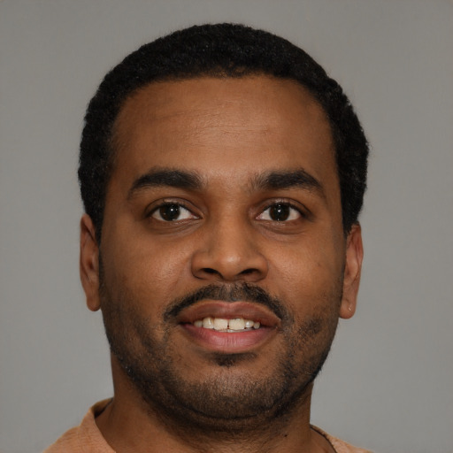 Joyful black young-adult male with short  brown hair and brown eyes