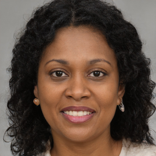 Joyful black young-adult female with long  brown hair and brown eyes